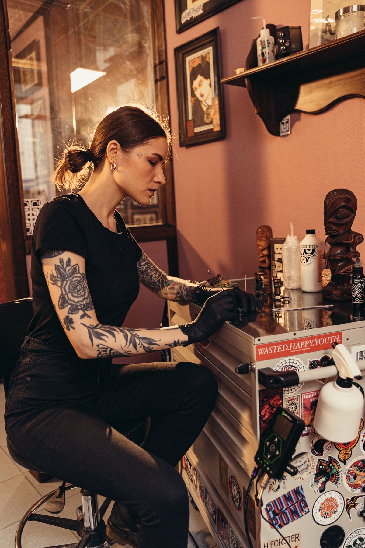 Tattoo artist concentrating on her work in a warmly decorated studio