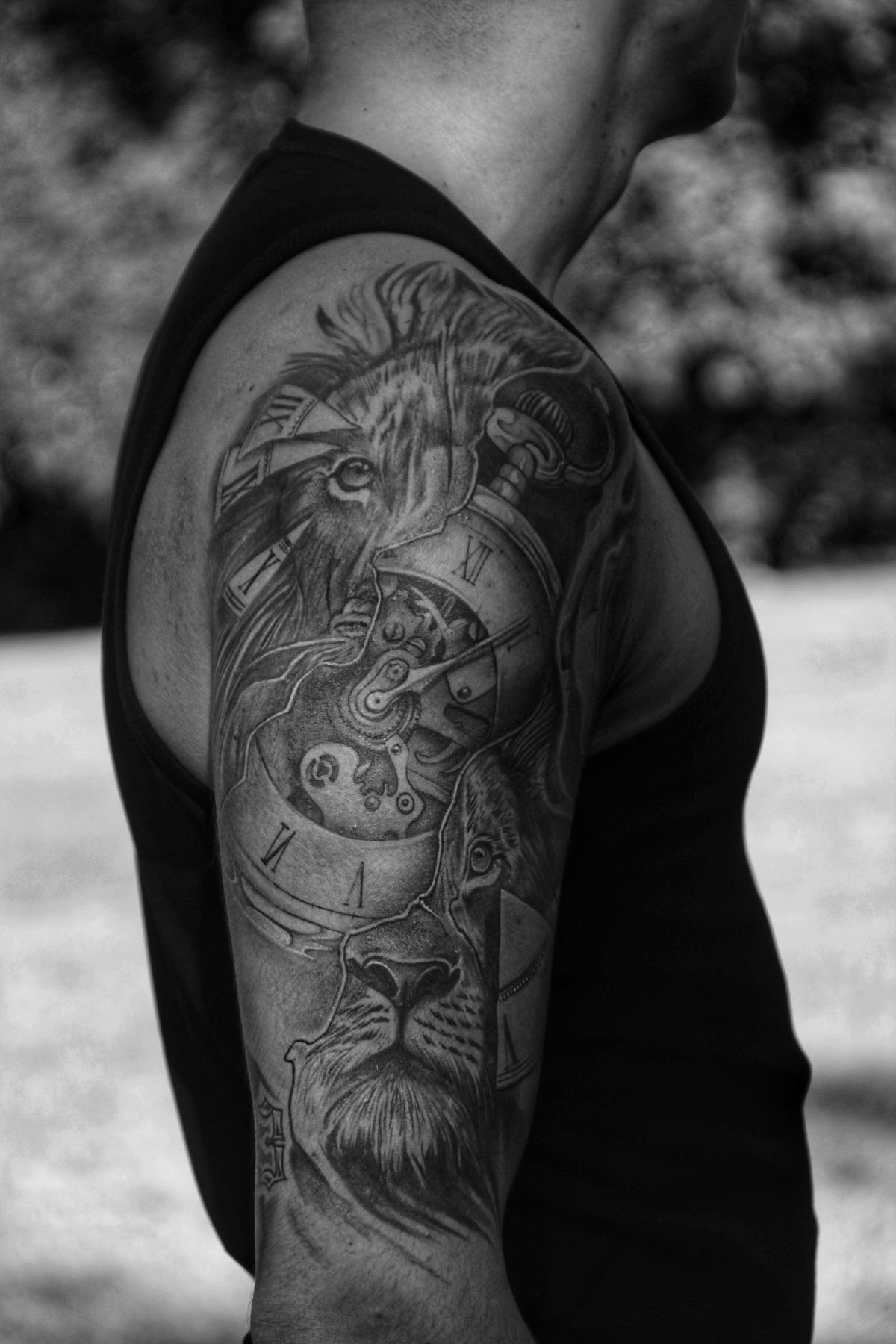 Detailed black and grey lion and clock tattoo on a man's arm