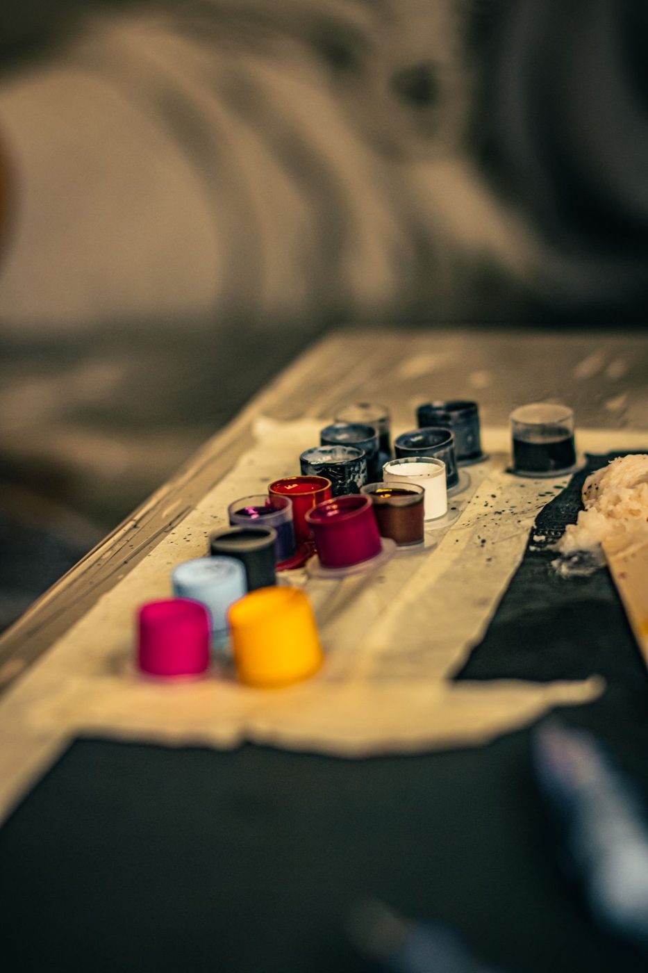 Small ink caps in red, yellow and dark colors lined up on a tattoo station tray