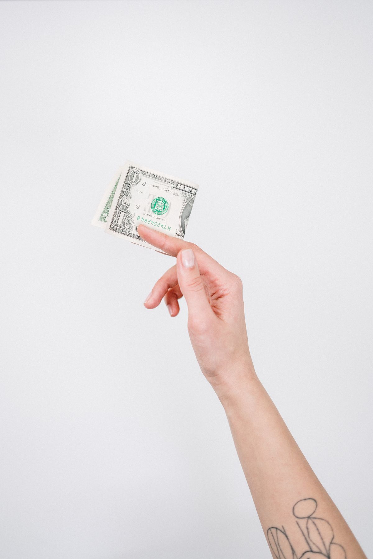 Tattooed hand holding a US dollar bill