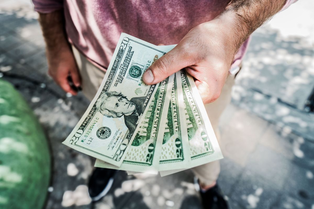 Hand holding a fan of twenty dollar bills