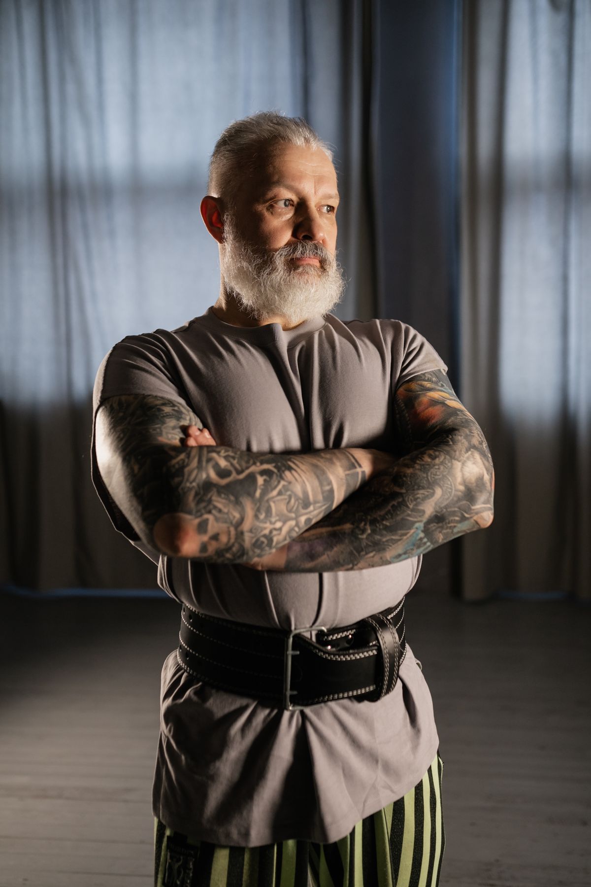 Elderly man with tattoos and a beard standing confidently