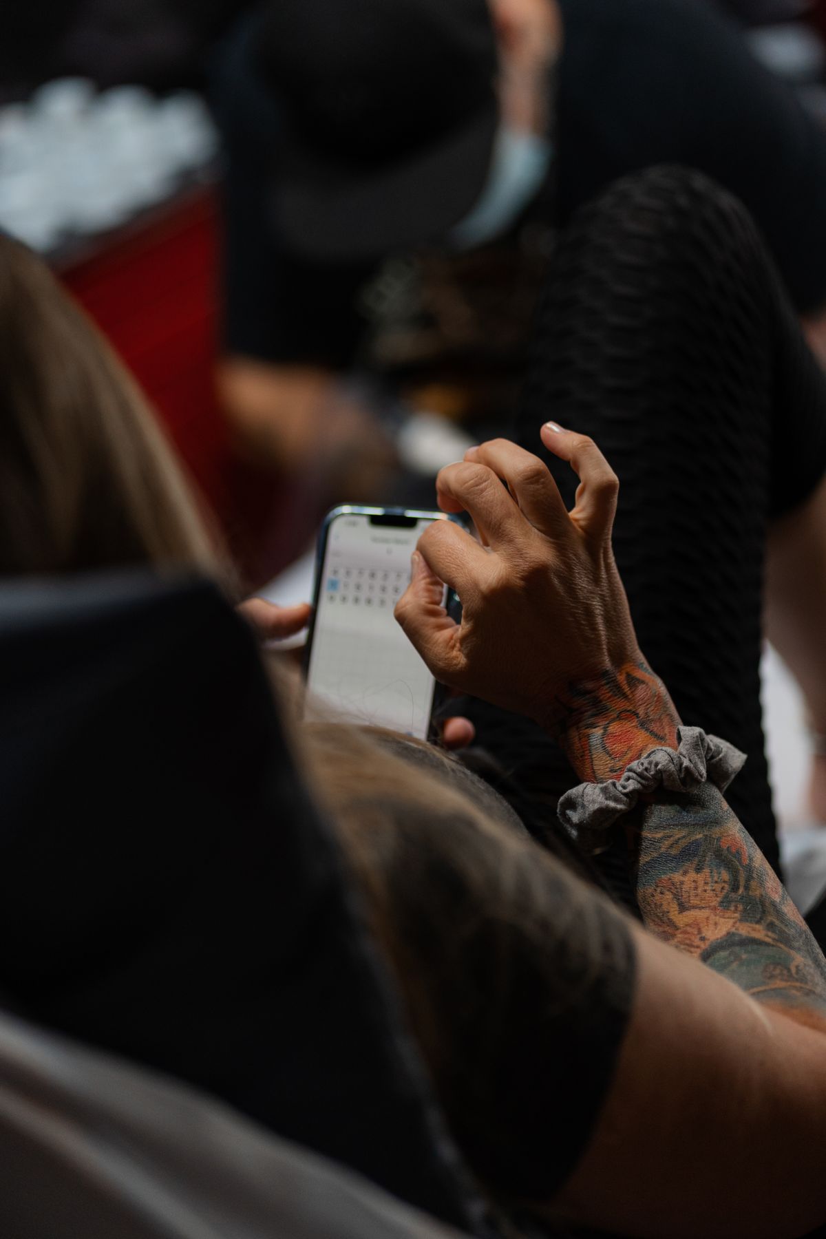 Close-up of a tattooed arm holding a smartphone