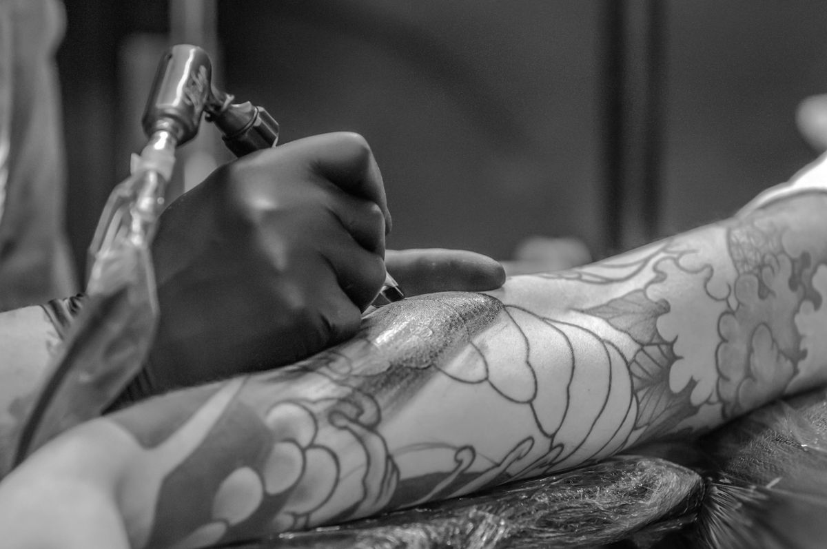Black and white close-up of the tattooing process on an arm