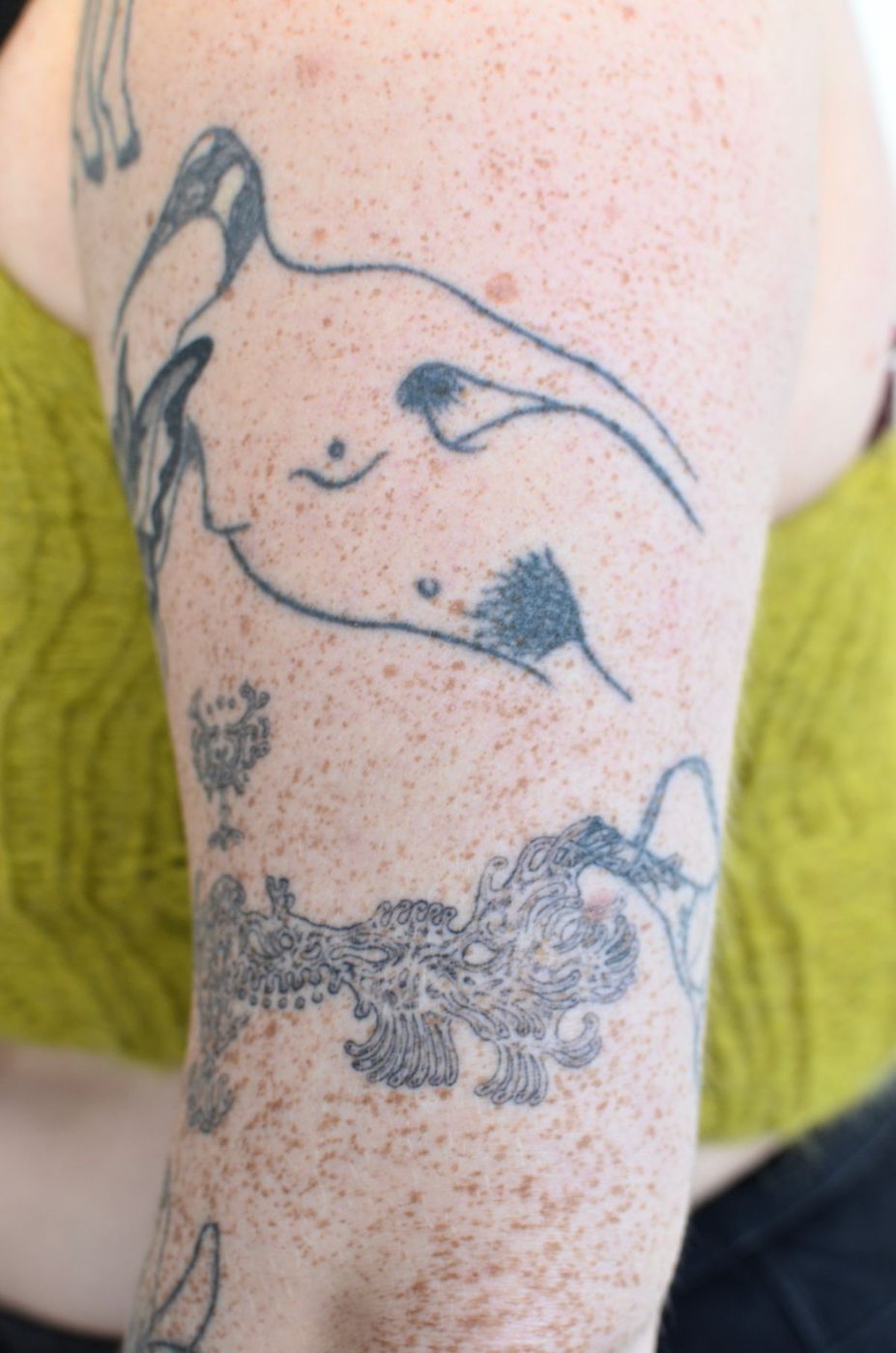 Upper arm with several separate blue-ink illustrations spread across pale skin