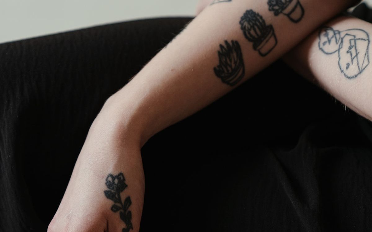 Forearm and hand with several small separate tattoos, including potted plants and line doodles