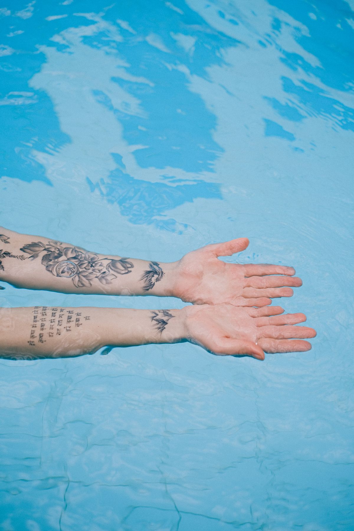 Tattooed arms submerged in swimming pool water