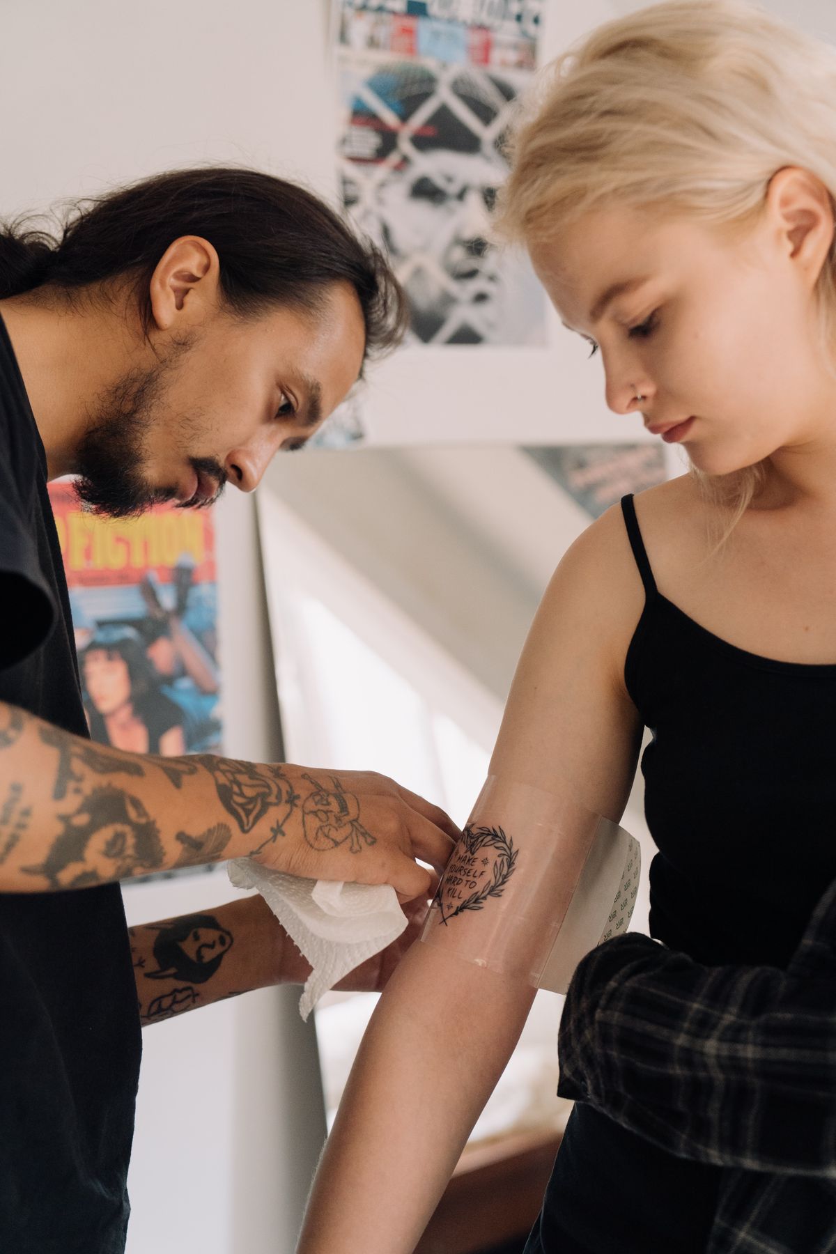Tattoo artist wrapping a fresh tattoo on a client's arm