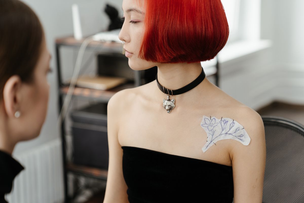 Tattoo artist transferring a new floral design onto skin