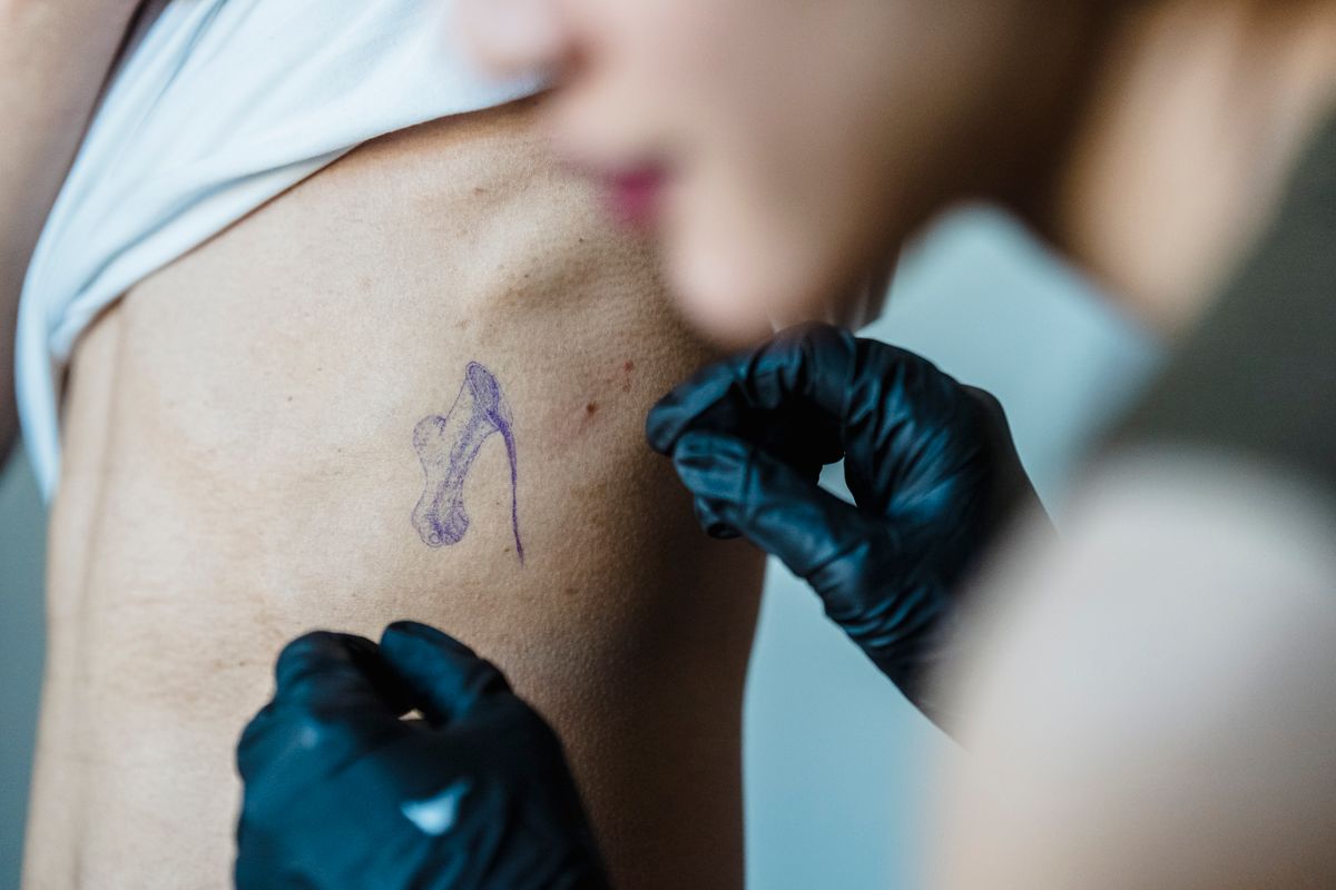 Tattoo artist applying a stencil to a client's ribs