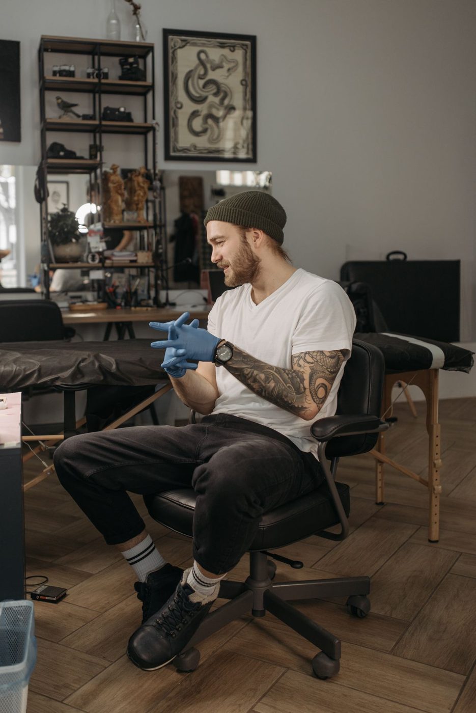 Tattoo artist in a white t-shirt seated in a chair in a tattoo studio